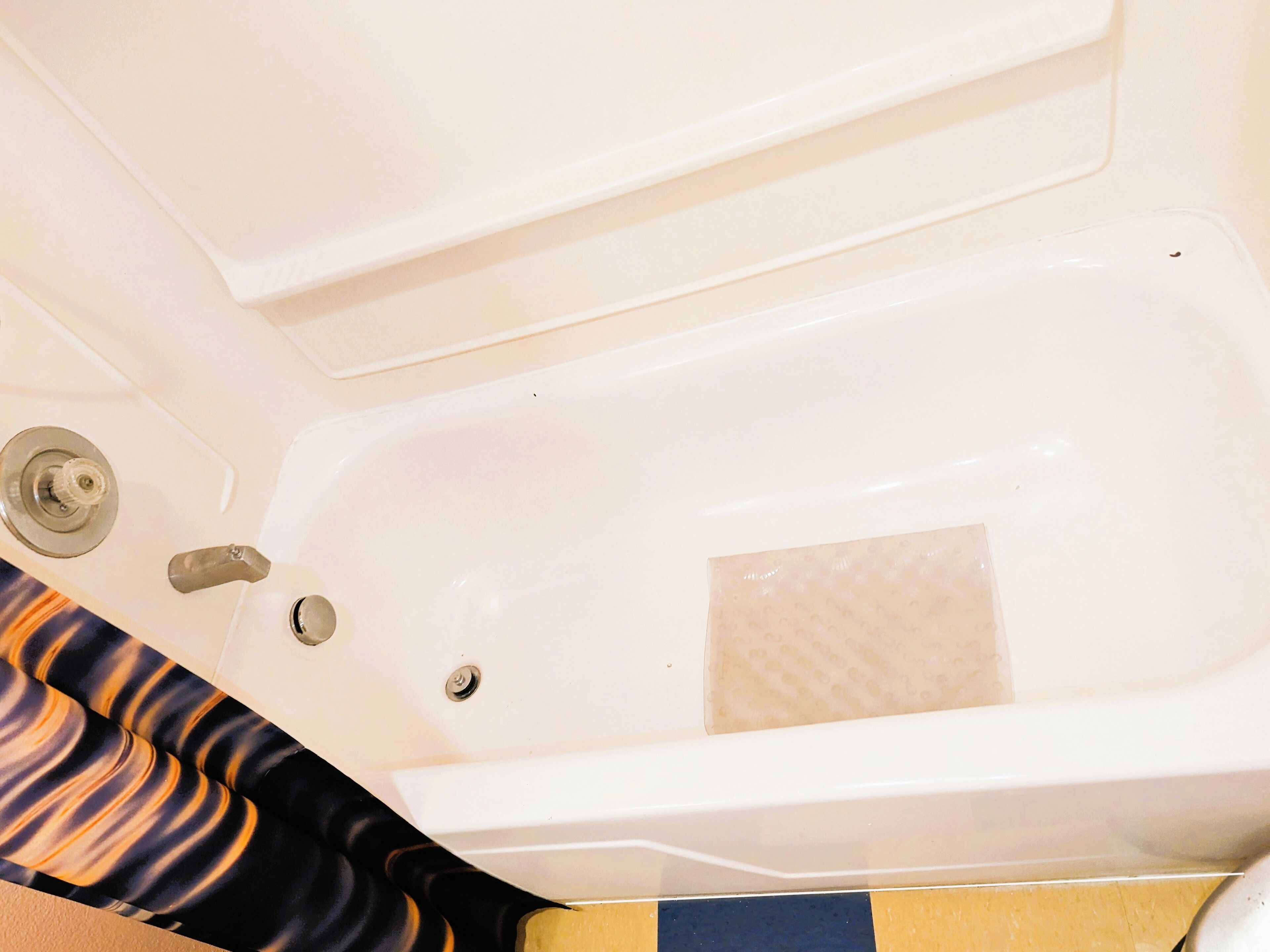 Une baignoire avec un robinet et un drain, un porte-serviettes et un sol carrelé.
