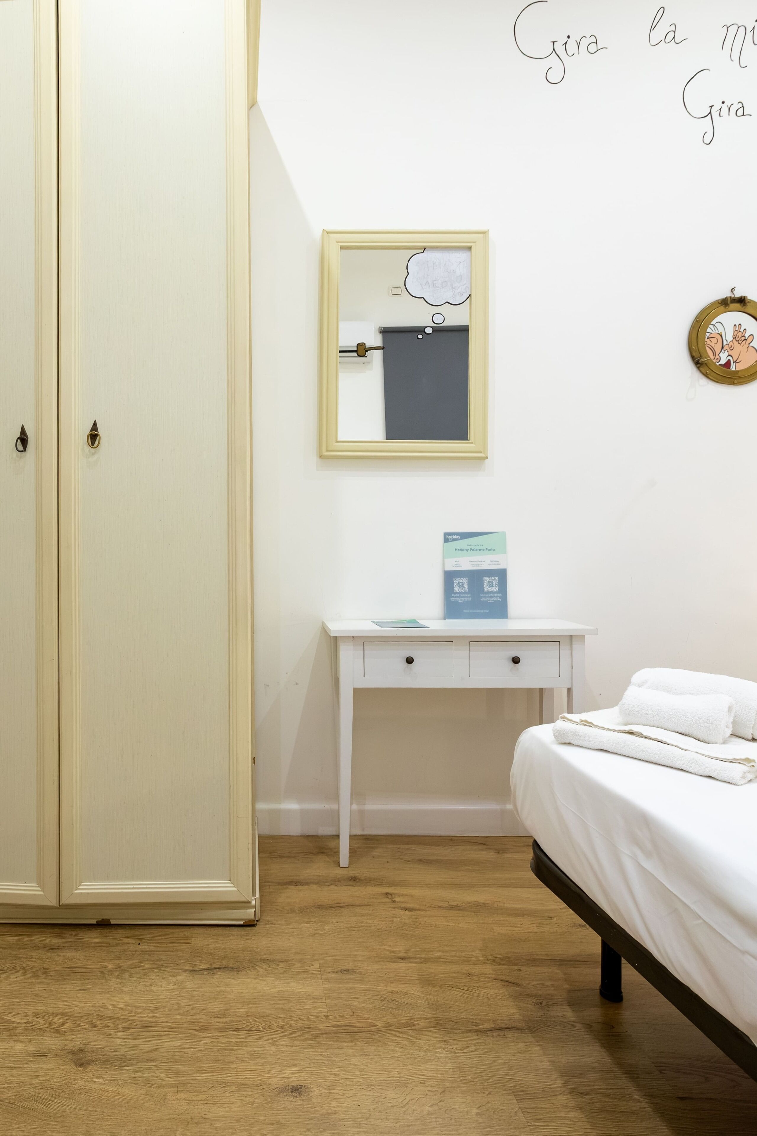 A bedroom with a bed, a bedside table, a mirror, and a wardrobe.
