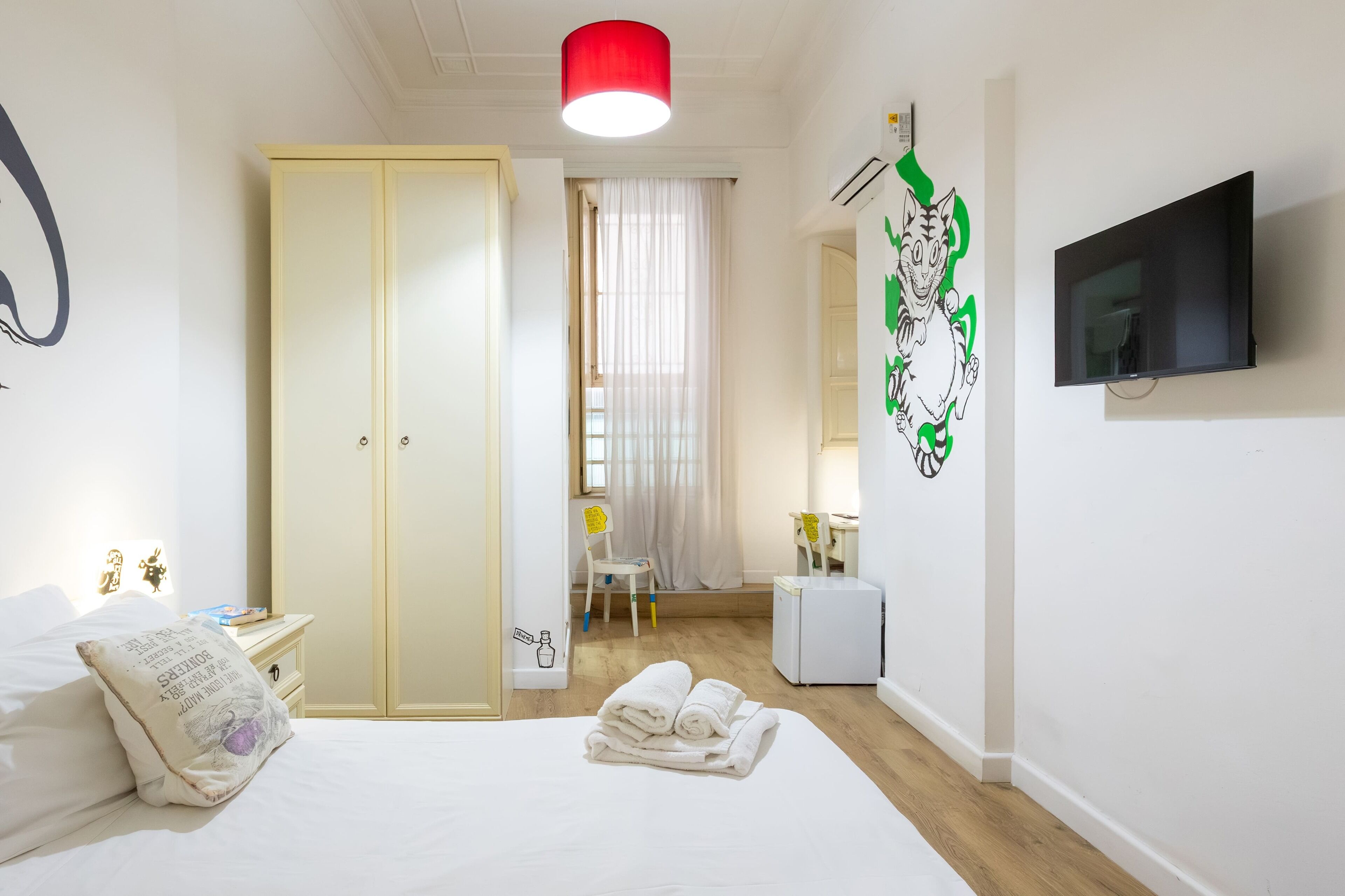 Hotelkamer met een bed, een kledingkast, een bureau met stoel, een televisie en een decoratie aan de muur.