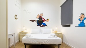 A bedroom with a bed, bedside tables, and a wall with cartoon characters. - Hotiday Palermo Porto (Palermo)