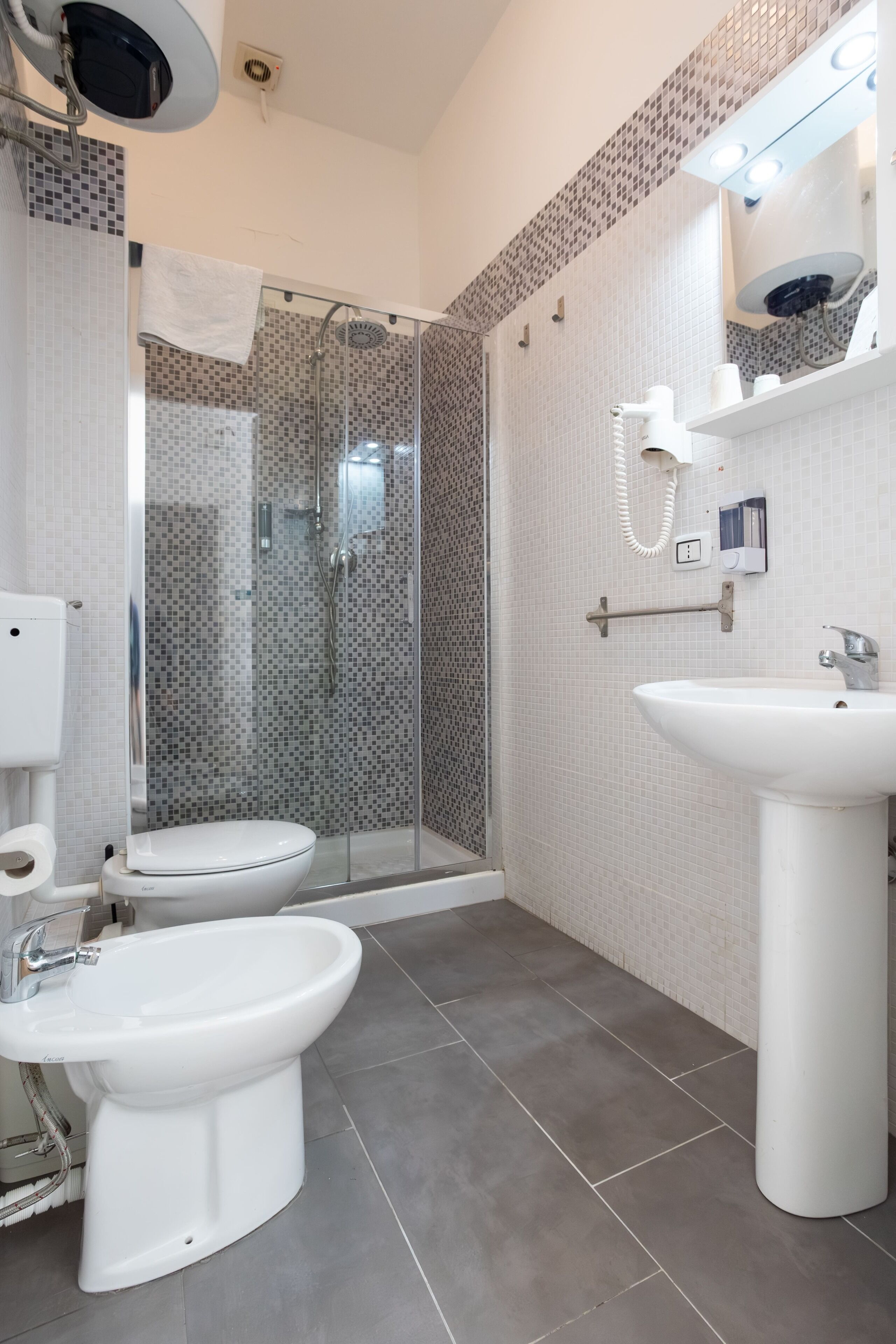 Un baño moderno con inodoro, bidé y ducha con cerramiento de vidrio.