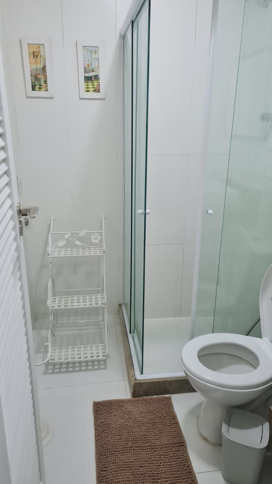 Un baño con cabina de ducha de vidrio, un inodoro y un lavabo blanco.
