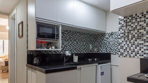 A compact kitchen with white cabinets, a black countertop, a microwave, and a tiled backsplash. - 3 Minutes From Copacabana Beach Nsc220 (Rio de Janeiro)