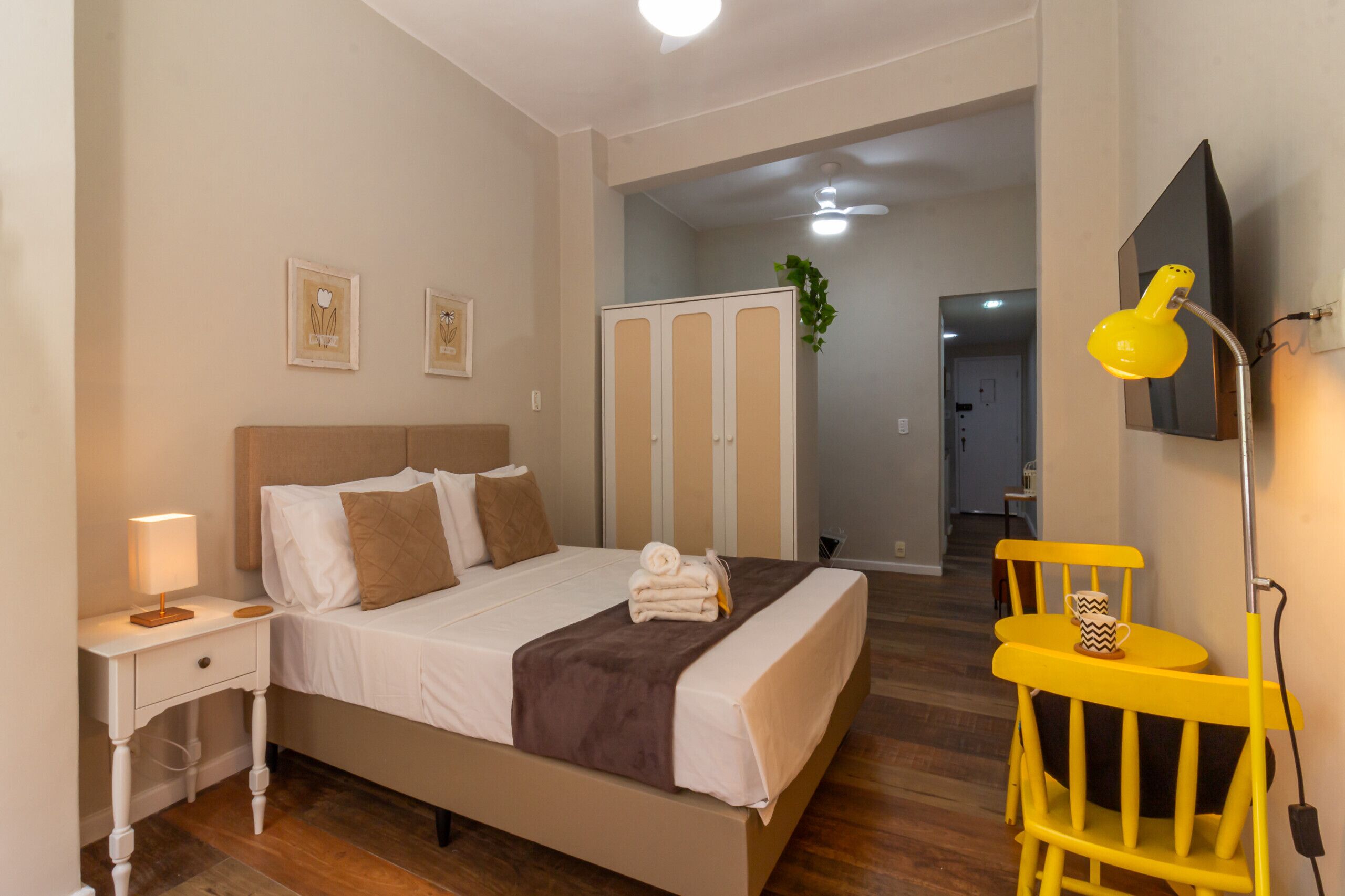 A bedroom with a bed, bedside table, lamp, and a chair.