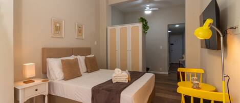 A bedroom with a bed, bedside table, lamp, and a chair.