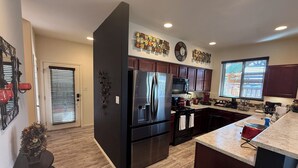 Een moderne keuken met een centraal eiland, roestvrijstalen apparatuur en een decoratief wandkunstwerk.