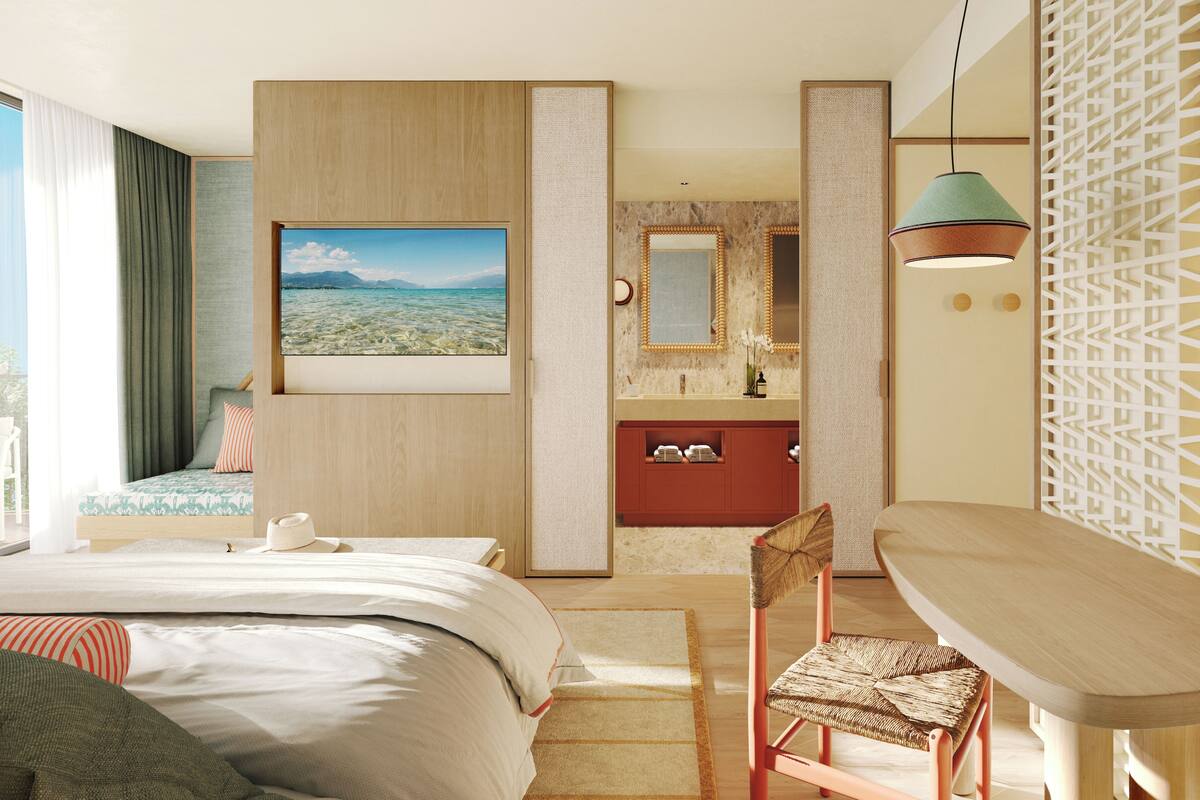 A modern hotel room with a large bed, a desk, a chair, a bathroom with a mirror, and a view of the outdoors.