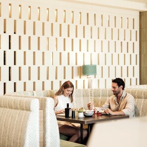 A modern interior with a patterned wall, a sofa, a table with a lamp, and a small plant. - Falkensteiner Resort Lake Garda (Salò)