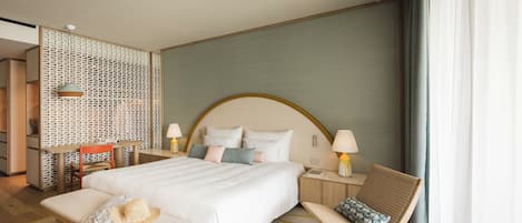 Una habitación de hotel con una cama grande, un banco de madera, una silla, una mesita pequeña y un panel decorativo en la pared.