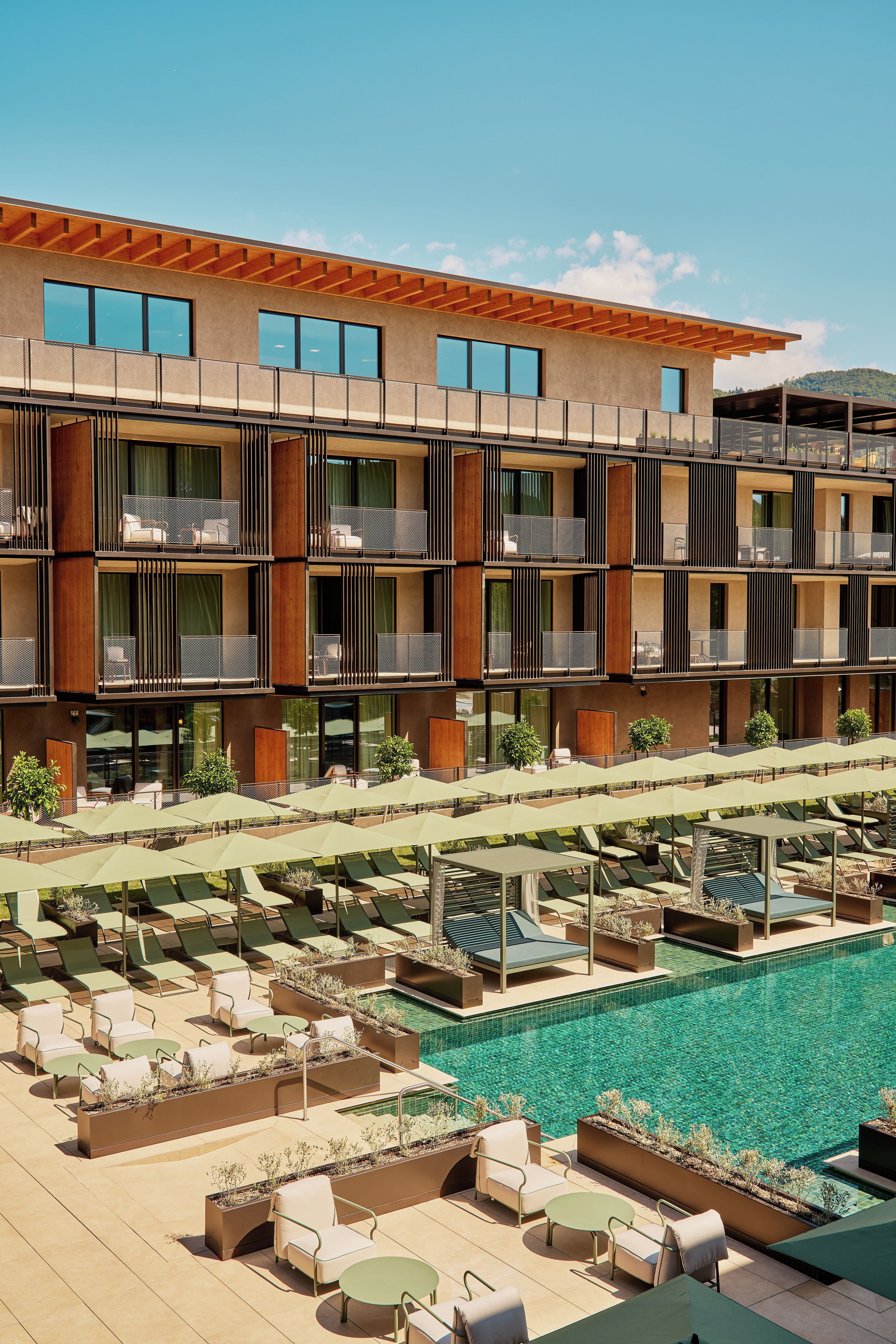 Un hotel con varios balcones, mobiliario exterior y una piscina.
