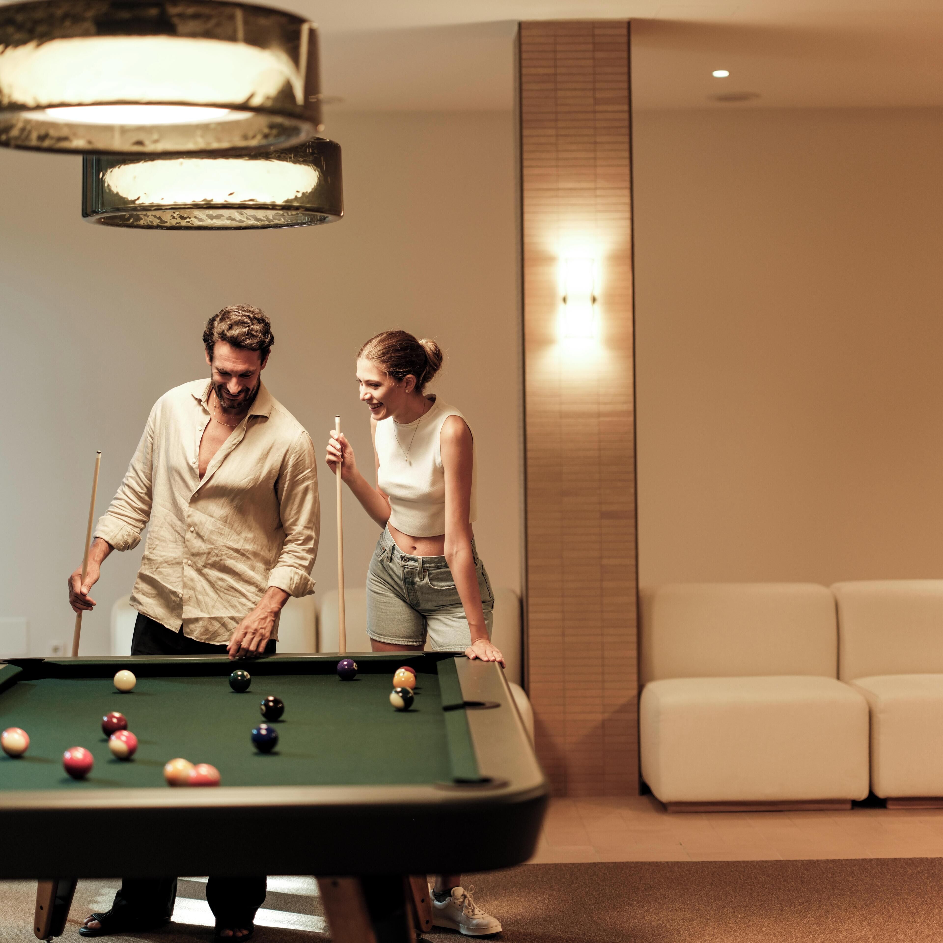 A pool table with balls, a sofa, and a wall with a light fixture.