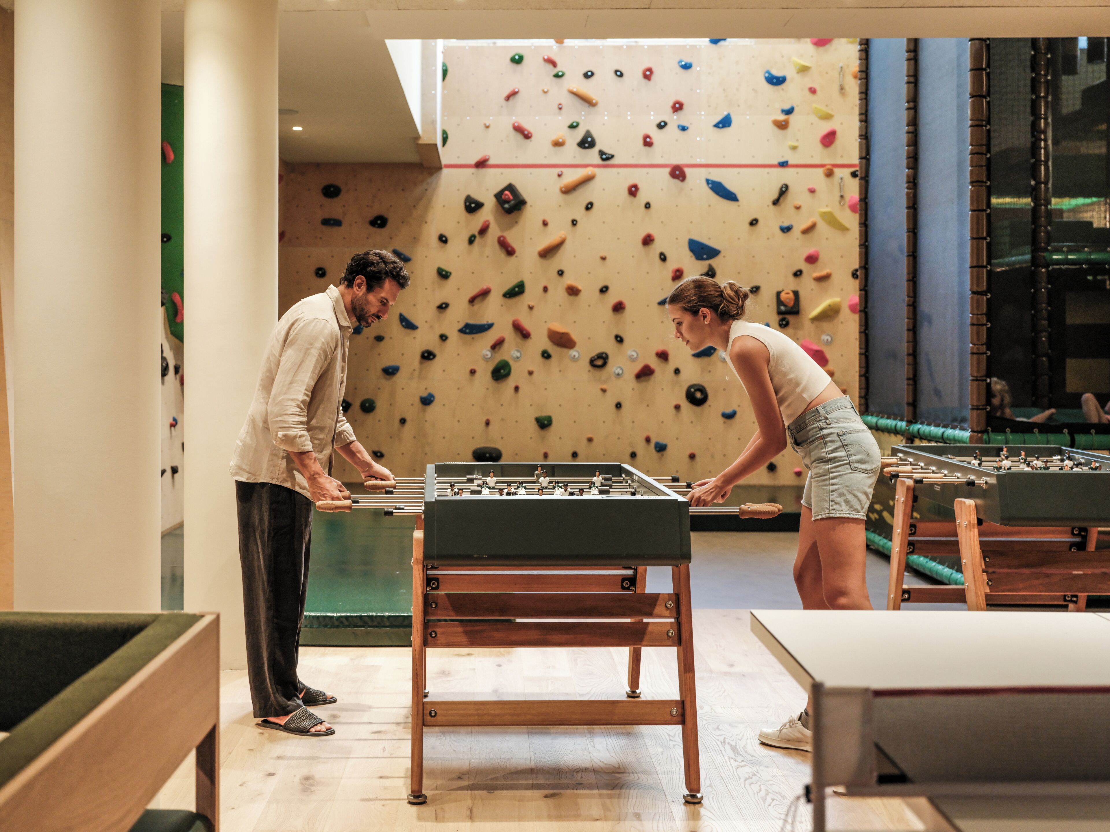 Ein Zimmer mit Tischfußball und einer Kletterwand.