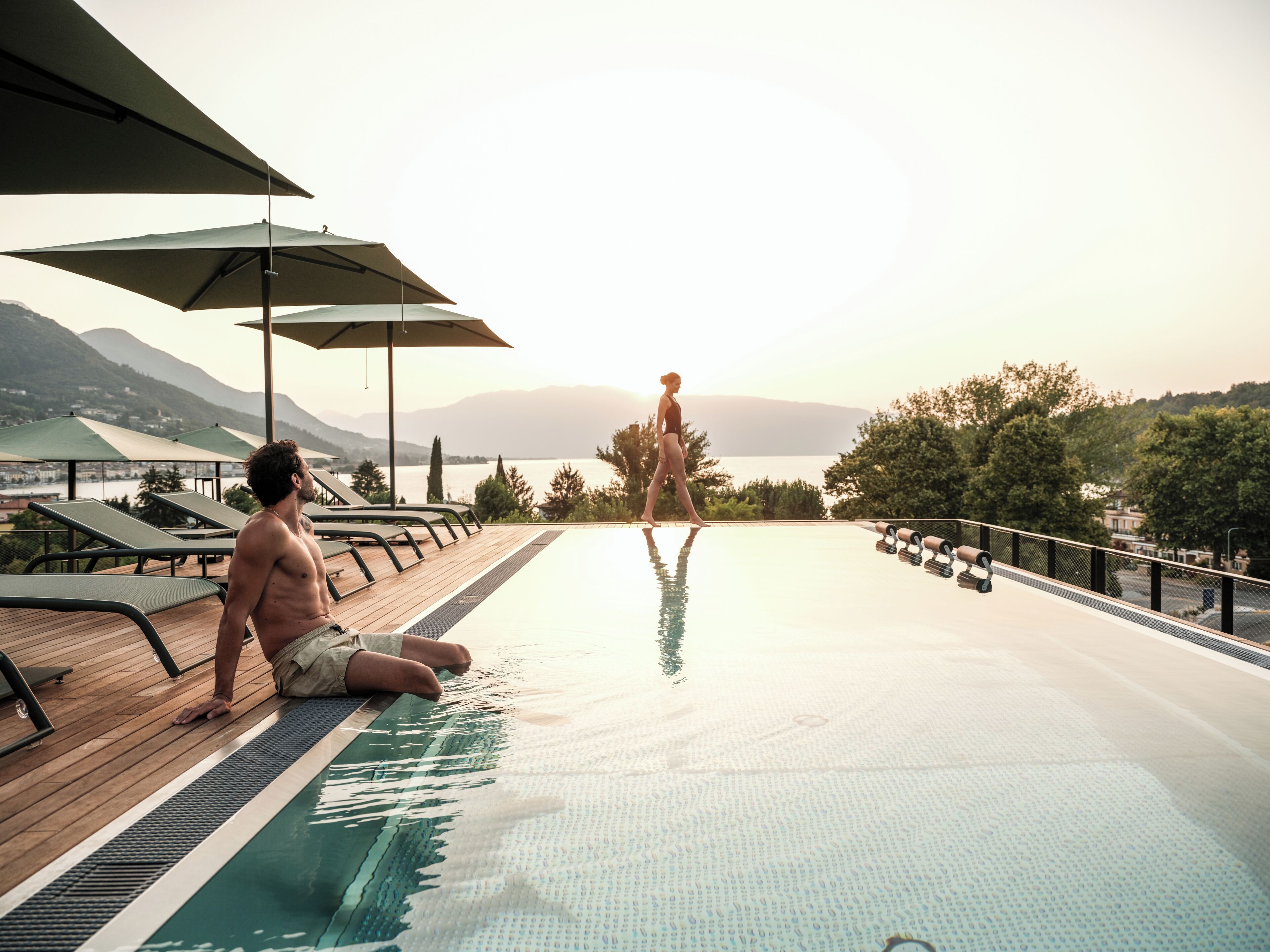 A poolside area with lounge chairs, umbrellas, and a view of the mountains.