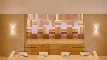 Un baño moderno con un espejo grande, varios lavamanos e iluminación empotrada.
