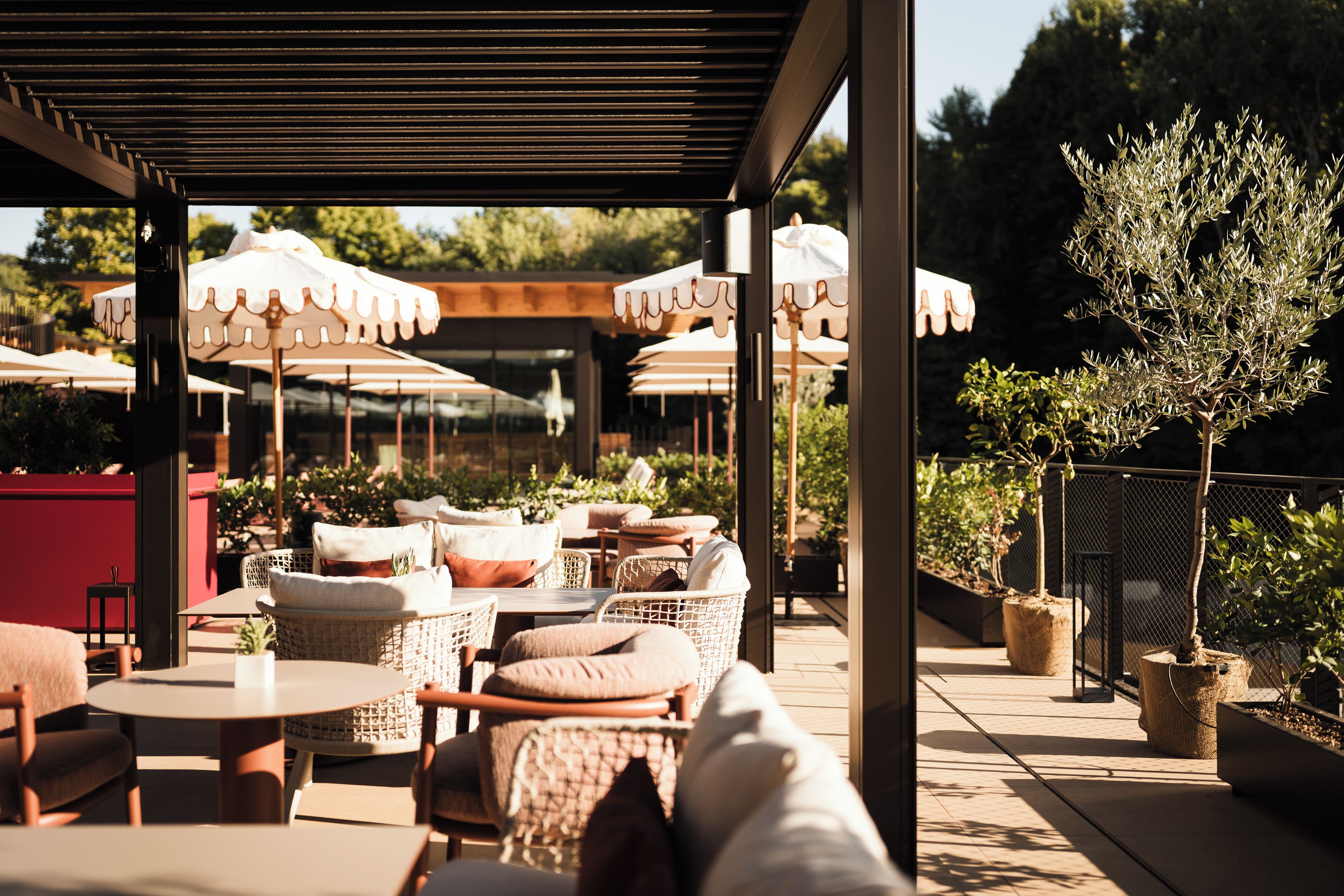 Een terras met tafels, stoelen, parasols en potplanten.