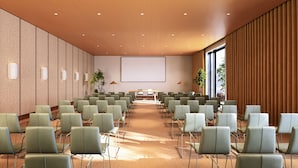 A conference room with rows of chairs, a large screen, and a wooden ceiling.