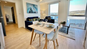 Un coin repas moderne avec une table blanche, deux chaises et un canapé bleu.