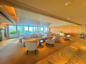 A spacious lobby with a large seating area, a reception desk, and large windows offering a view of the cityscape. - Brickell Building - Miami's financial district - We Host (Miami)