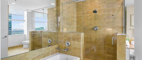 Un baño moderno con ducha envuelta en vidrio, una bañera grande y vistas a la ciudad a través de la ventana.