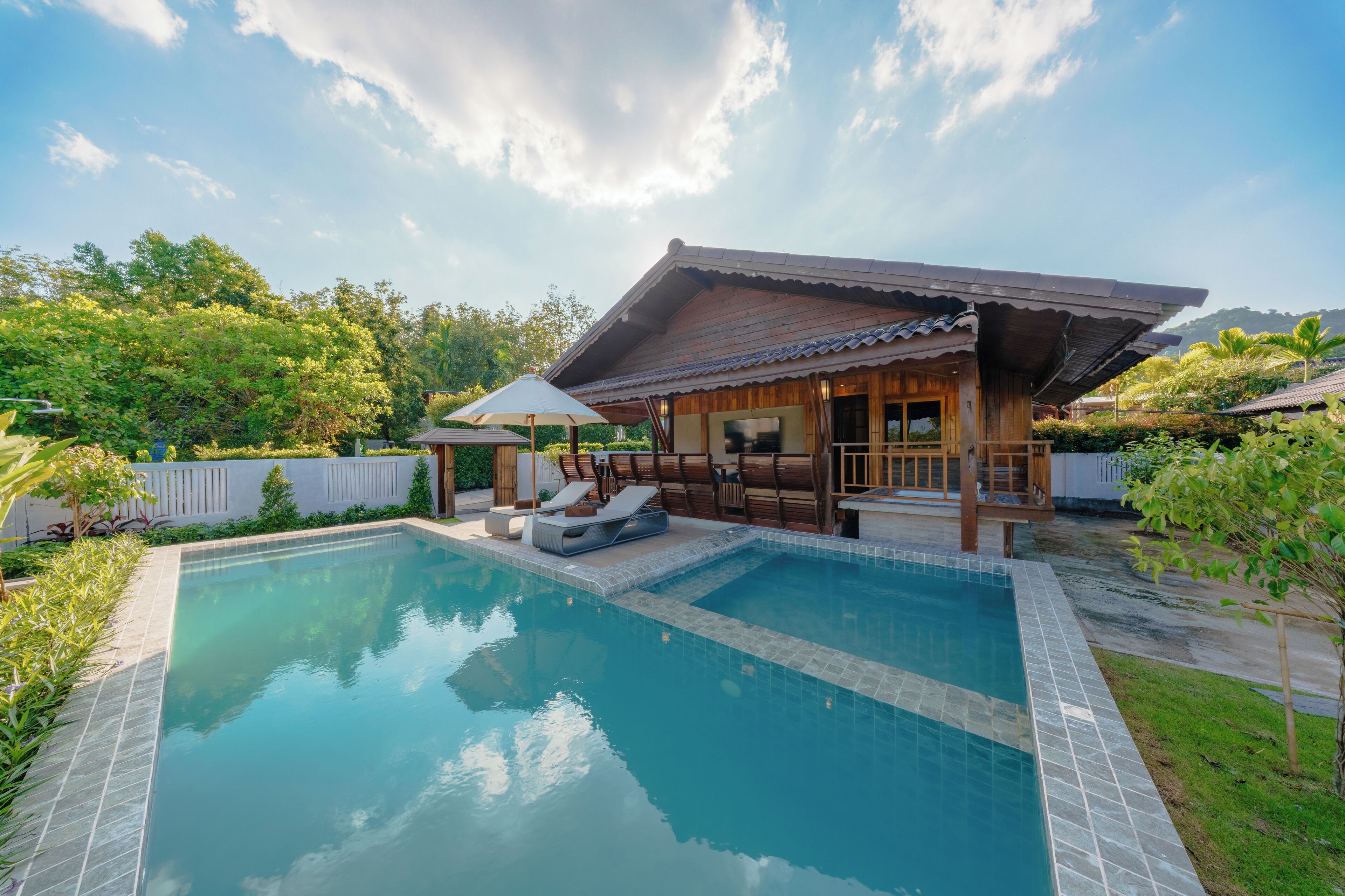 A swimming pool with lounge chairs and a wooden structure with a tiled roof.