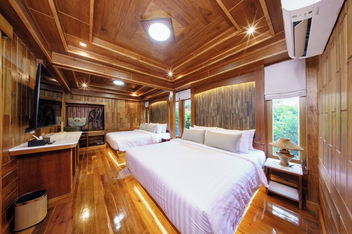 Een houten kamer in chaletstijl met twee bedden, een bureau en een televisie.