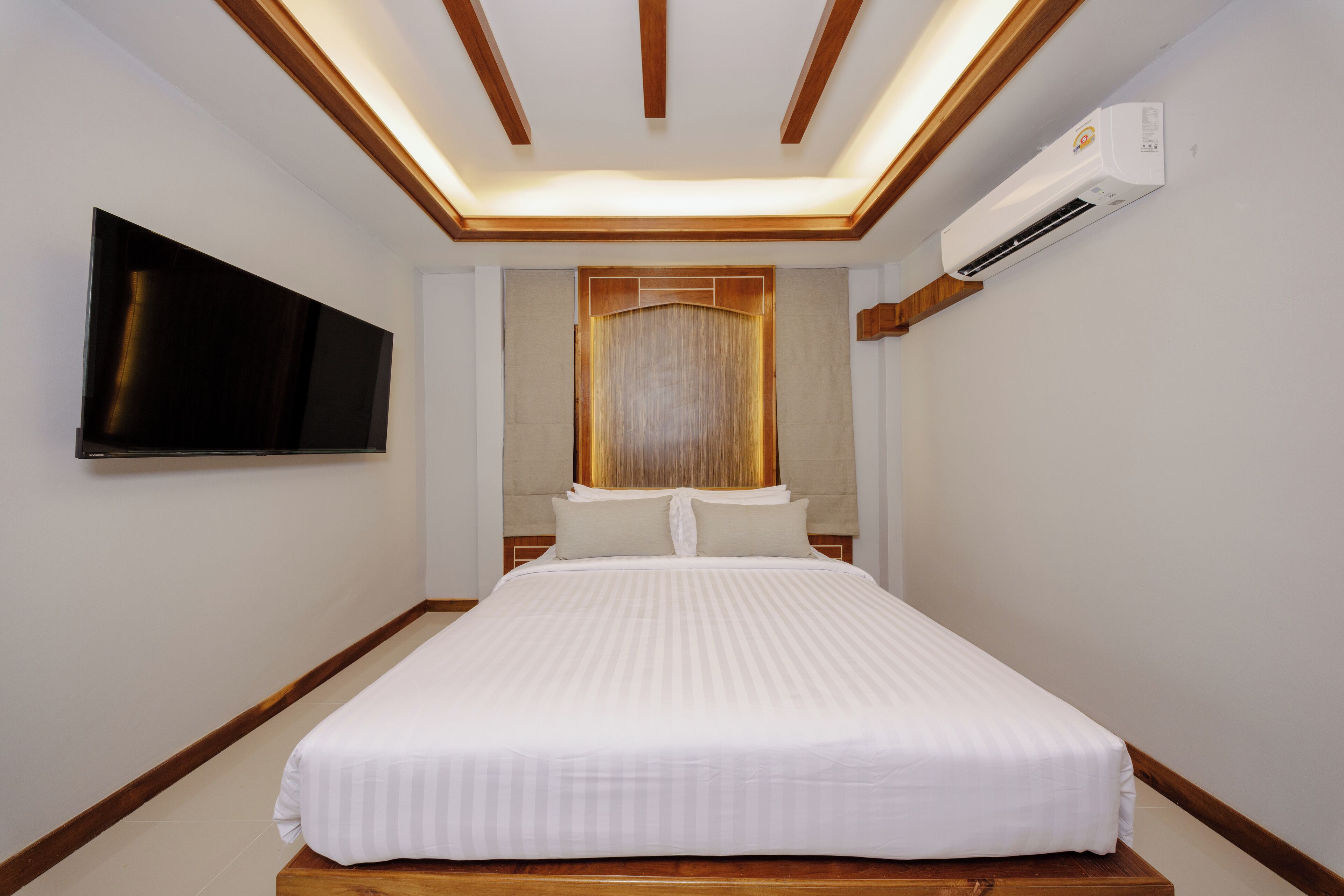 Une chambre d’hôtel équipée d’un lit, d’un téléviseur à écran plat, d’un système de climatisation et d’une fenêtre avec des rideaux.
