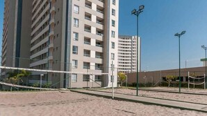 A sandy beach area with volleyball nets, surrounded by tall residential buildings. - RESORT: 2 adultos e 1 criança a 4km do Thermas Lar. e a 3km do Hot Beach (Olímpia)
