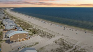 Ein Hotel an der Küste mit Blick auf den Strand, mit einem großen Sandstrand, dem Meer und einer Reihe von Gebäuden direkt am Strand.