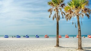 A beach with palm trees and beach umbrellas. - Modern & cheerful, private pool, near Disney (Kissimmee)