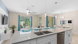 A modern kitchen with a large island, built-in dishwasher, and a ceiling fan. - Modern & cheerful, private pool, near Disney (Kissimmee)