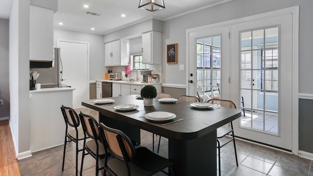 A modern kitchen with a central island, white cabinetry, and a large window. - Adorable Bungalow Near Tybee Beach (Savannah)