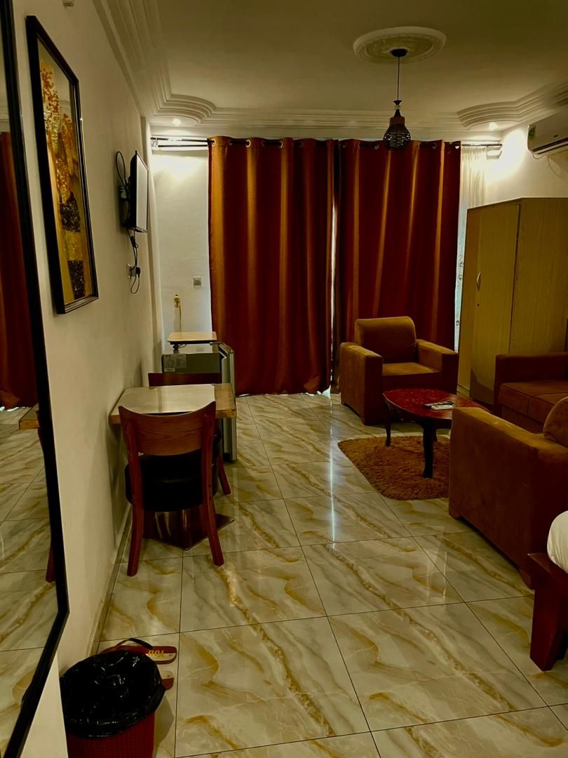 A living room with a dining area, a sofa, a red curtain, and a ceiling light.
