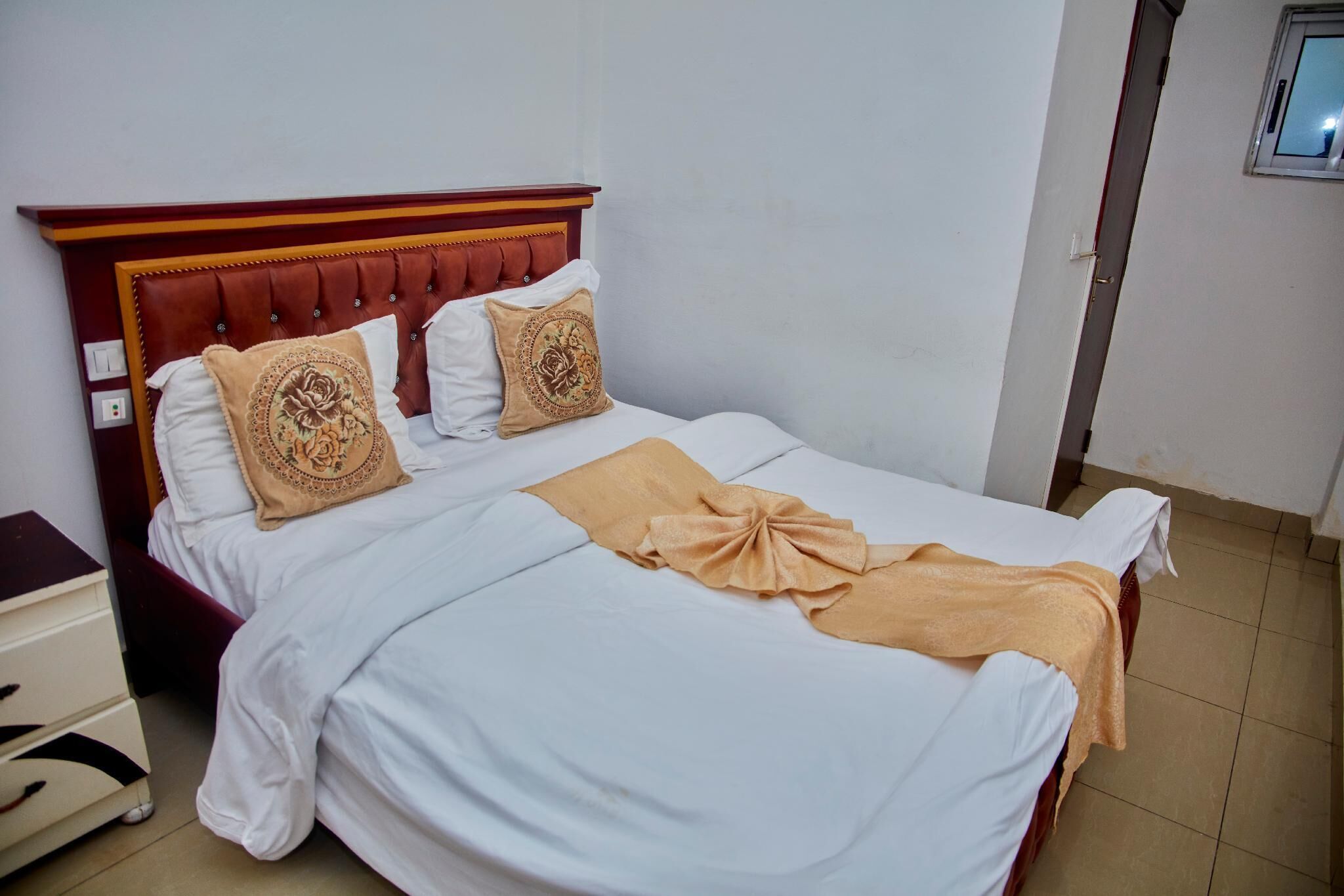 A neatly made bed with a wooden headboard, white bedding, and decorative pillows.