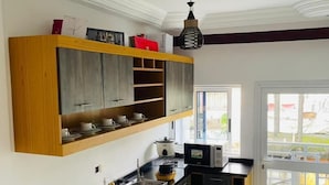 A modern kitchen with wooden cabinets, a black countertop, and a built-in oven. - Résidence hôtelière Samba (Douala)