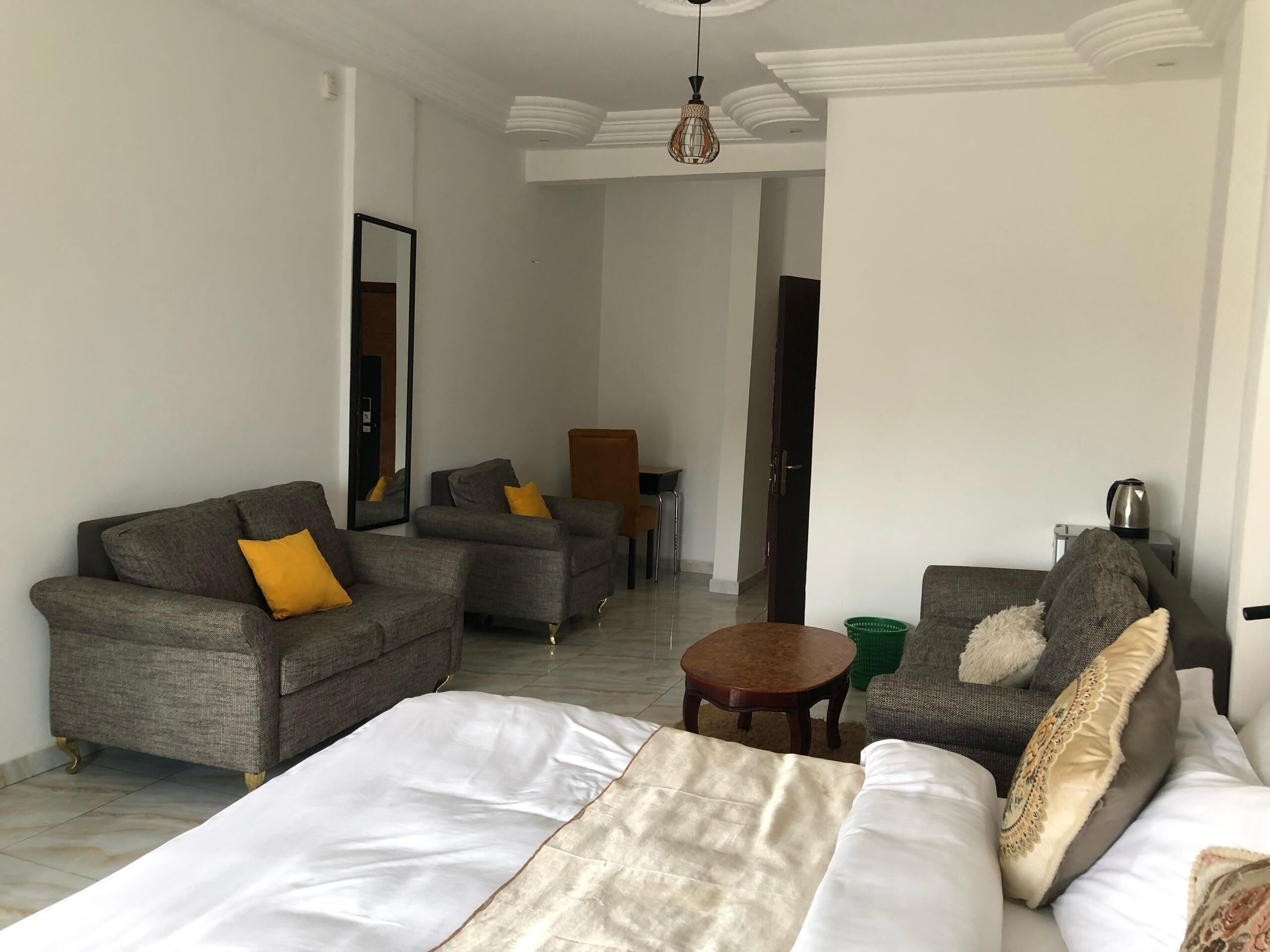 Une chambre d’hôtel avec un lit, deux canapés, une petite table et une chaise.