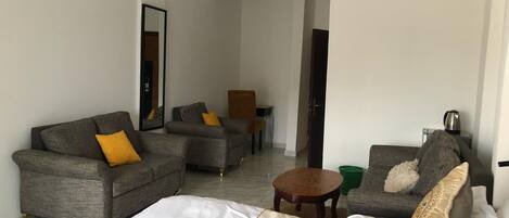 Une chambre d’hôtel avec un lit, deux canapés, une petite table et une chaise.