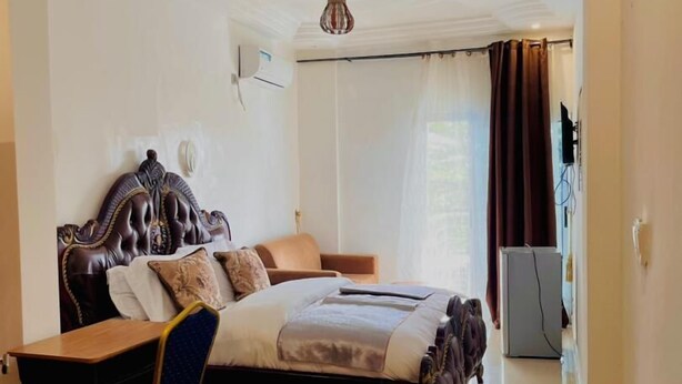 A bedroom with a bed, a desk, a chair, a ceiling fan, and a TV. - Résidence hôtelière Samba (Douala)