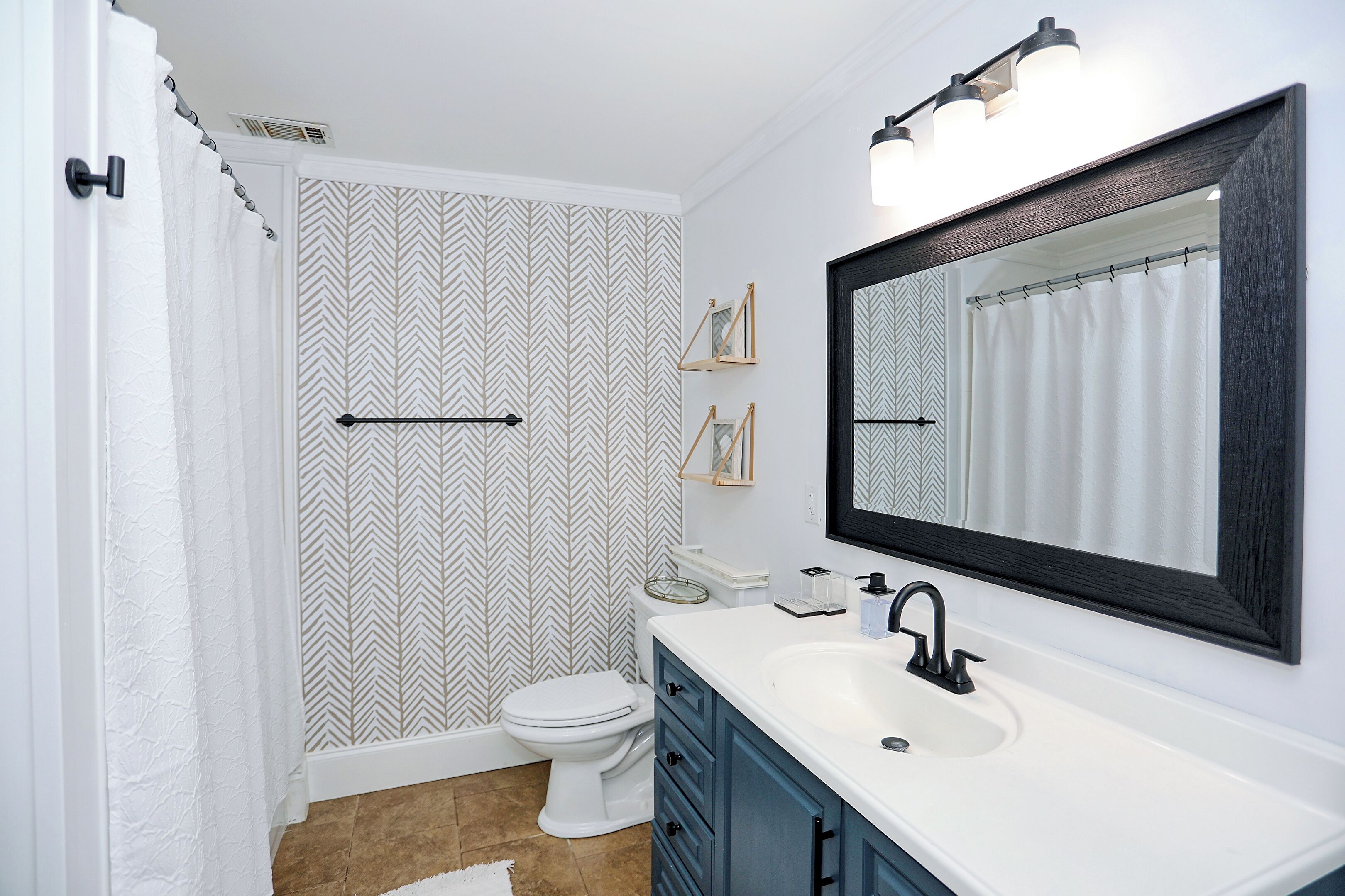 A bathroom with a white sink, a mirror, a toilet, and a shower curtain.
