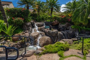 A waterfall surrounded by rocks and greenery, with a sign indicating no climbing.
