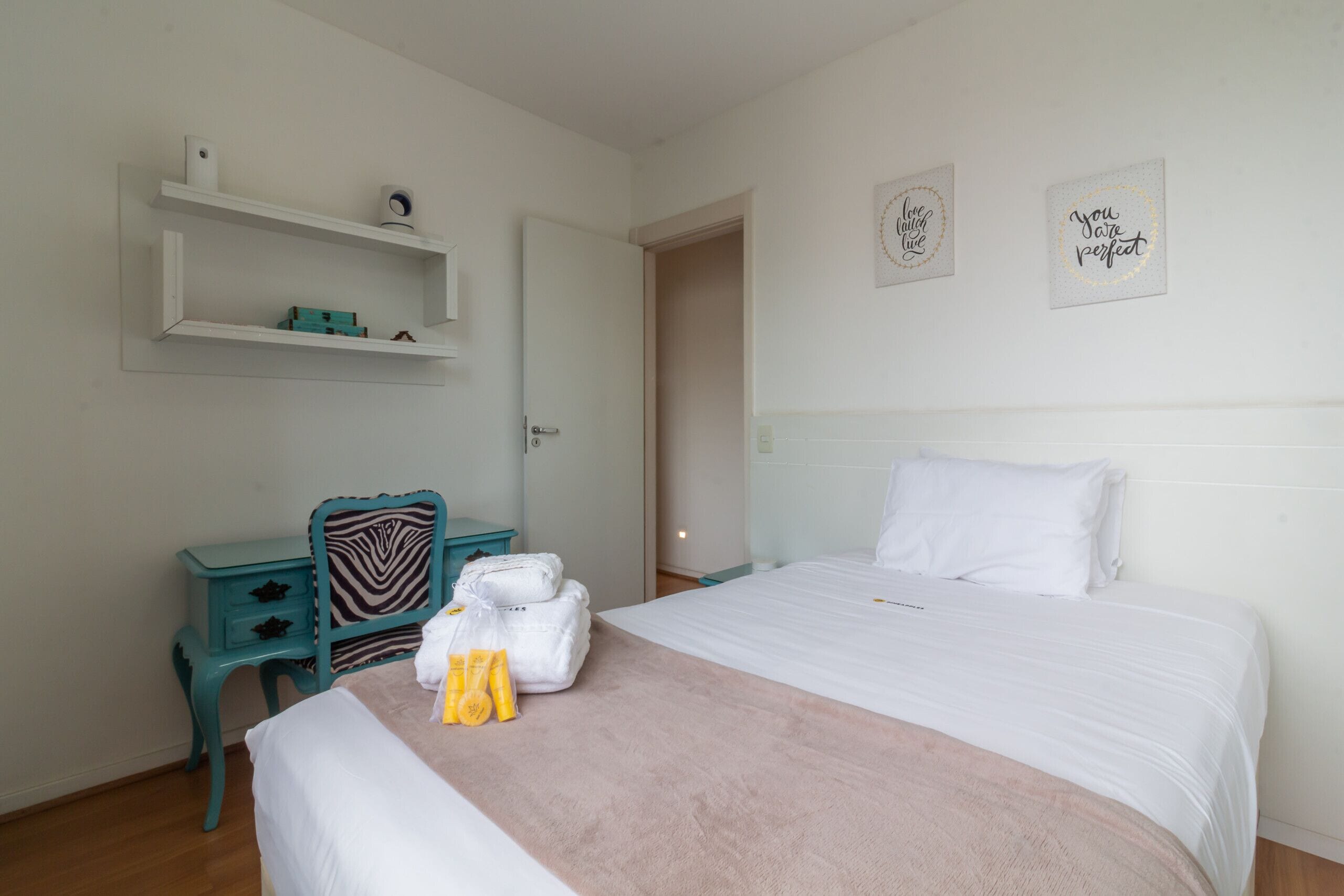 A bedroom with a bed, a desk, and two wall decorations.