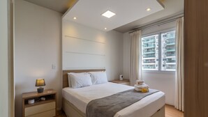 A modern bedroom with a large bed, bedside tables, a lamp, and a window with curtains. - 10 Minutes From the Olympic Park Pja802 (Rio de Janeiro)