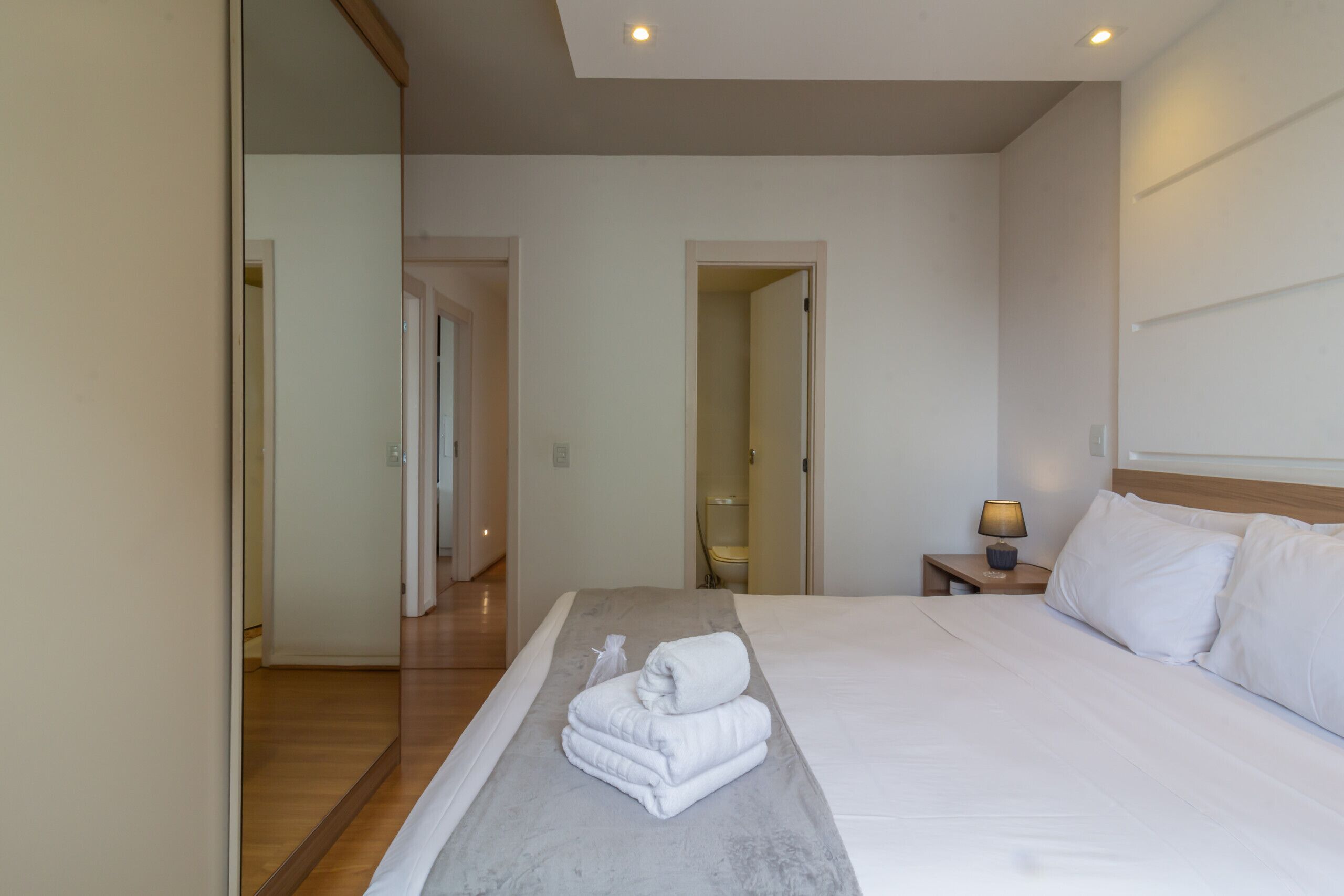 Une chambre d’hôtel avec un grand lit, une table de chevet avec une lampe et un miroir au mur.