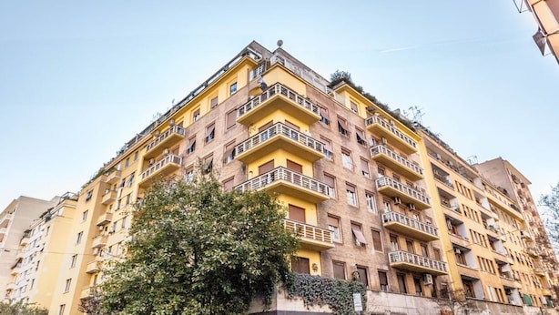 A multi-story building with balconies, a tree in front, and a clear sky. - Sapienza Apt - Modern House en Piazza Bologna (Rome)
