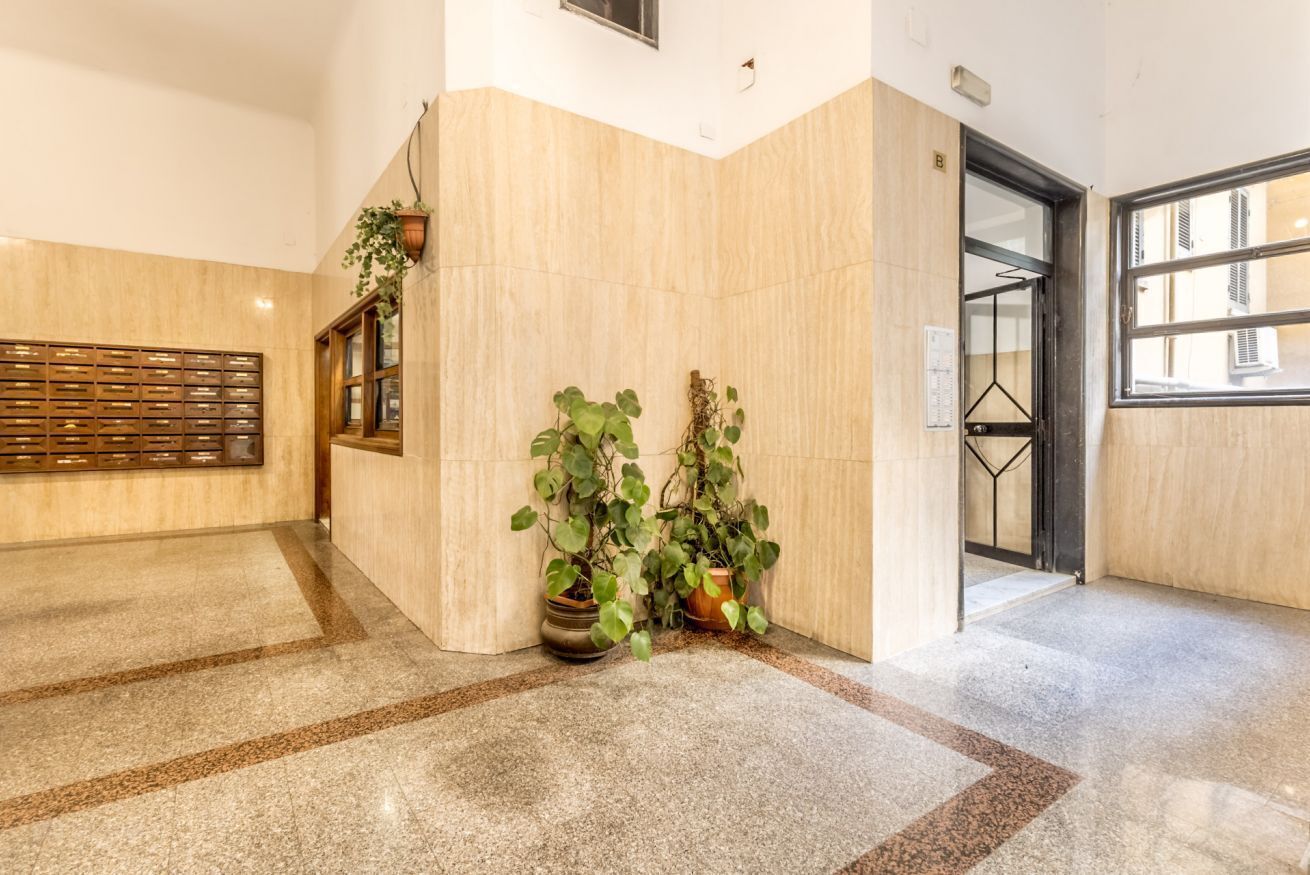 Un hall d’entrée spacieux avec un sol en marbre, un comptoir d’accueil en bois et des plantes en pot.