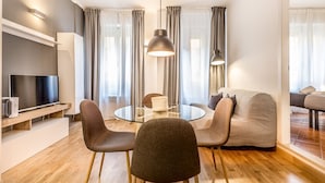 A modern living room with a round glass table, two chairs, a sofa, a TV, and a pendant light. - Sapienza Apt - Modern House en Piazza Bologna (Rome)
