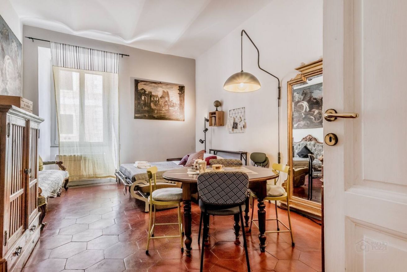 Un salon chaleureux avec une table à manger ronde, des sièges confortables, une cheminée et des œuvres d’art accrochées aux murs.