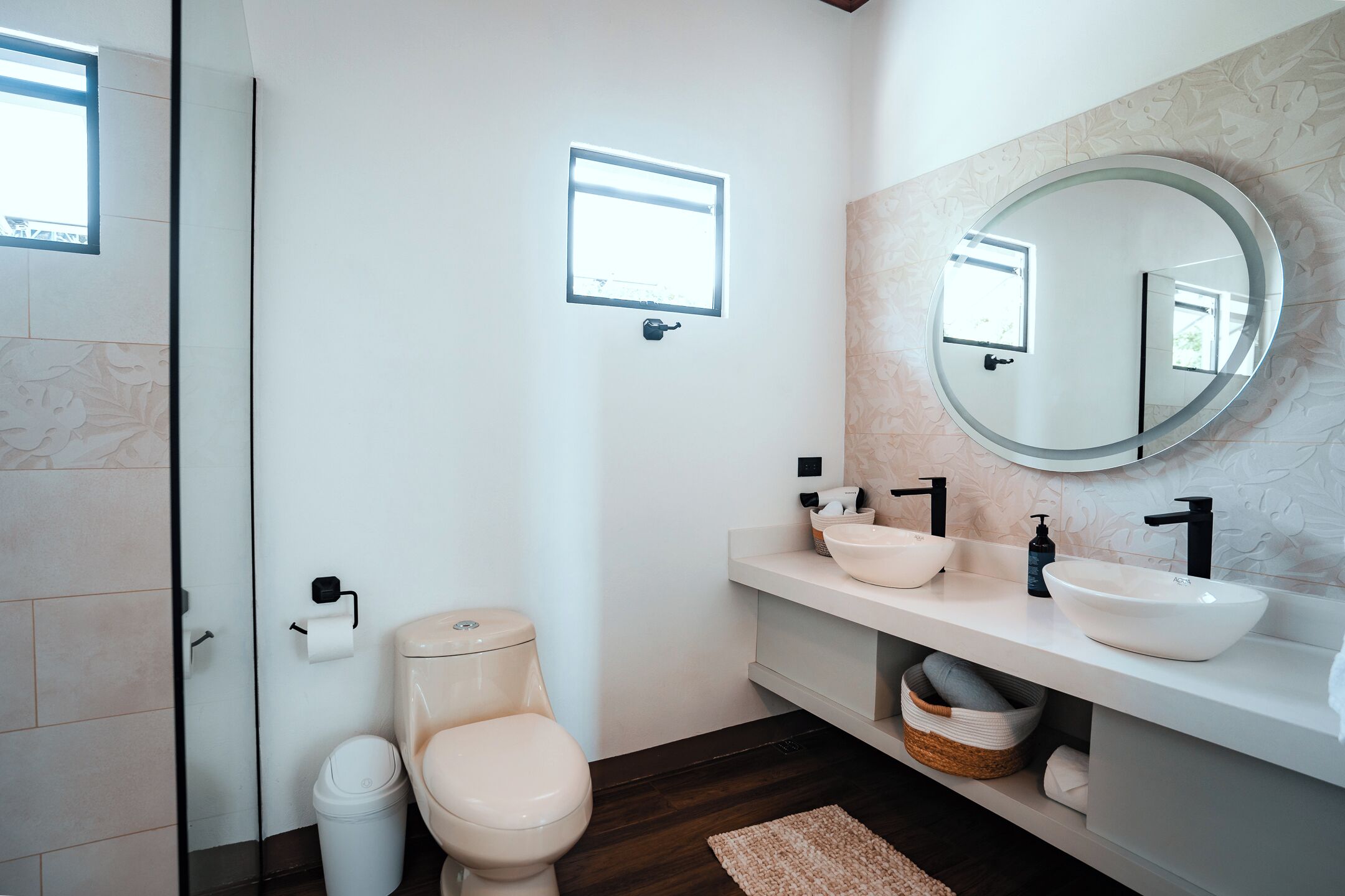 Een moderne badkamer met toilet, bidet en een grote spiegel.