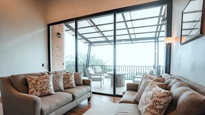 A modern living room with a sofa set, a coffee table, and a large sliding glass door leading to an outdoor area. - Casa Dalia (Monteverde)