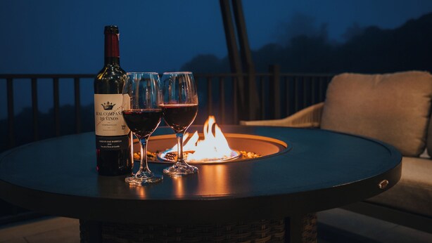 A table with a bottle of wine, two glasses, and a fire pit. - Casa Dalia (Monteverde)