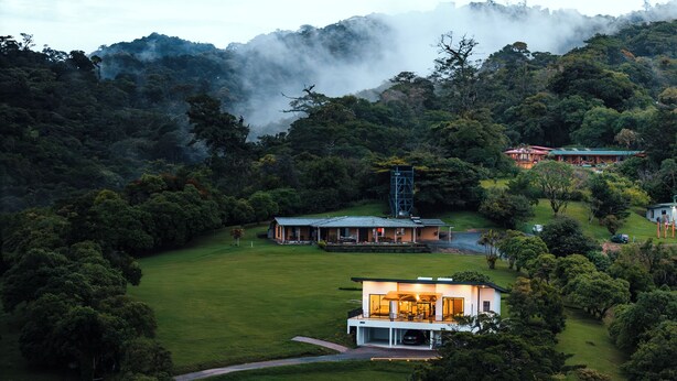 A modern house with a large open patio, surrounded by lush greenery and a river. - Casa Dalia (Monteverde)